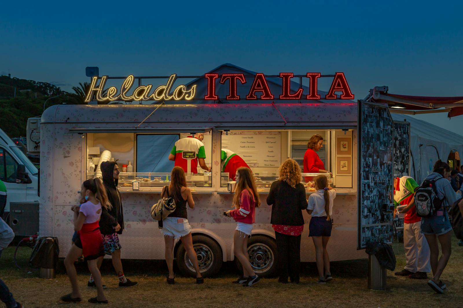 Night scene of Helados Italia ice cream truck with people enjoying treats in Argentina.